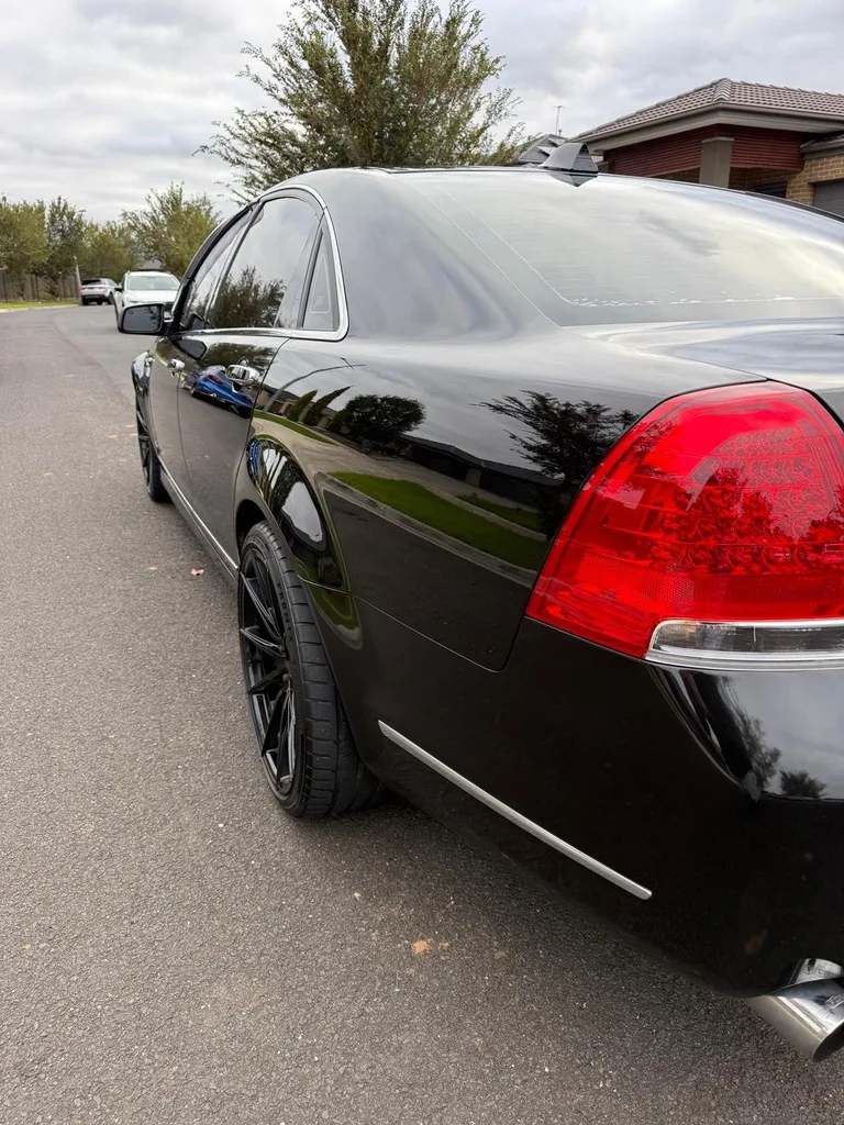 Deep gloss down the rear quarter of a detailed black sedan
